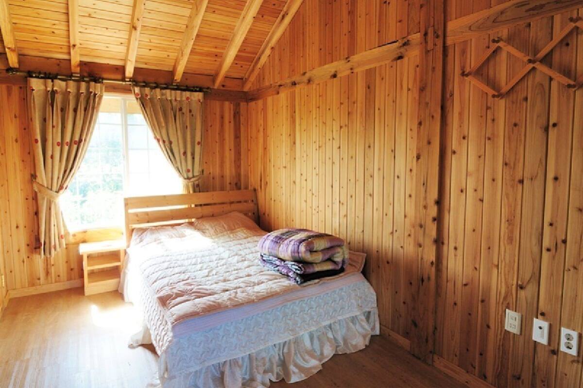 Une pièce en bois avec un lit, des rideaux et une fenêtre.