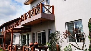 Un bâtiment doté d’un balcon, d’un espace extérieur aménagé pour s’asseoir et d’un mur en pierre.
