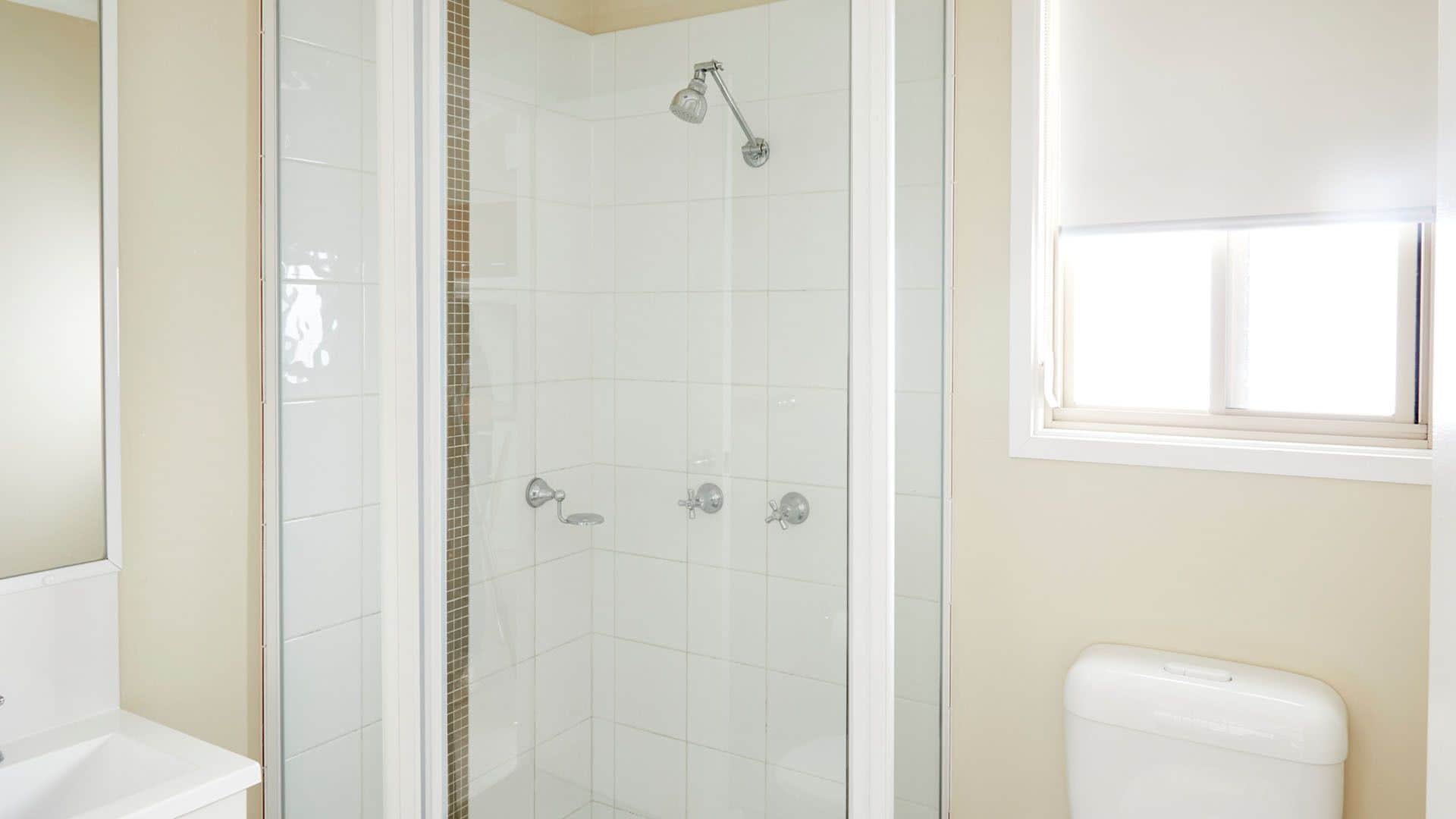 A bathroom with a glass-enclosed shower, a toilet, and a sink.