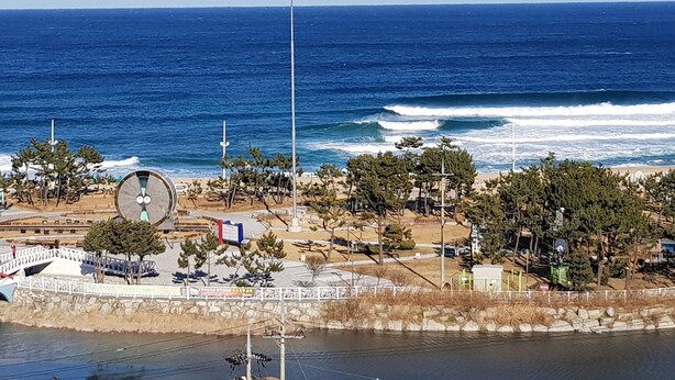A coastal area with a large circular structure, possibly a clock or monument, surrounded by trees and a paved walkway. - Hotel Tops Ville (Gangneung)