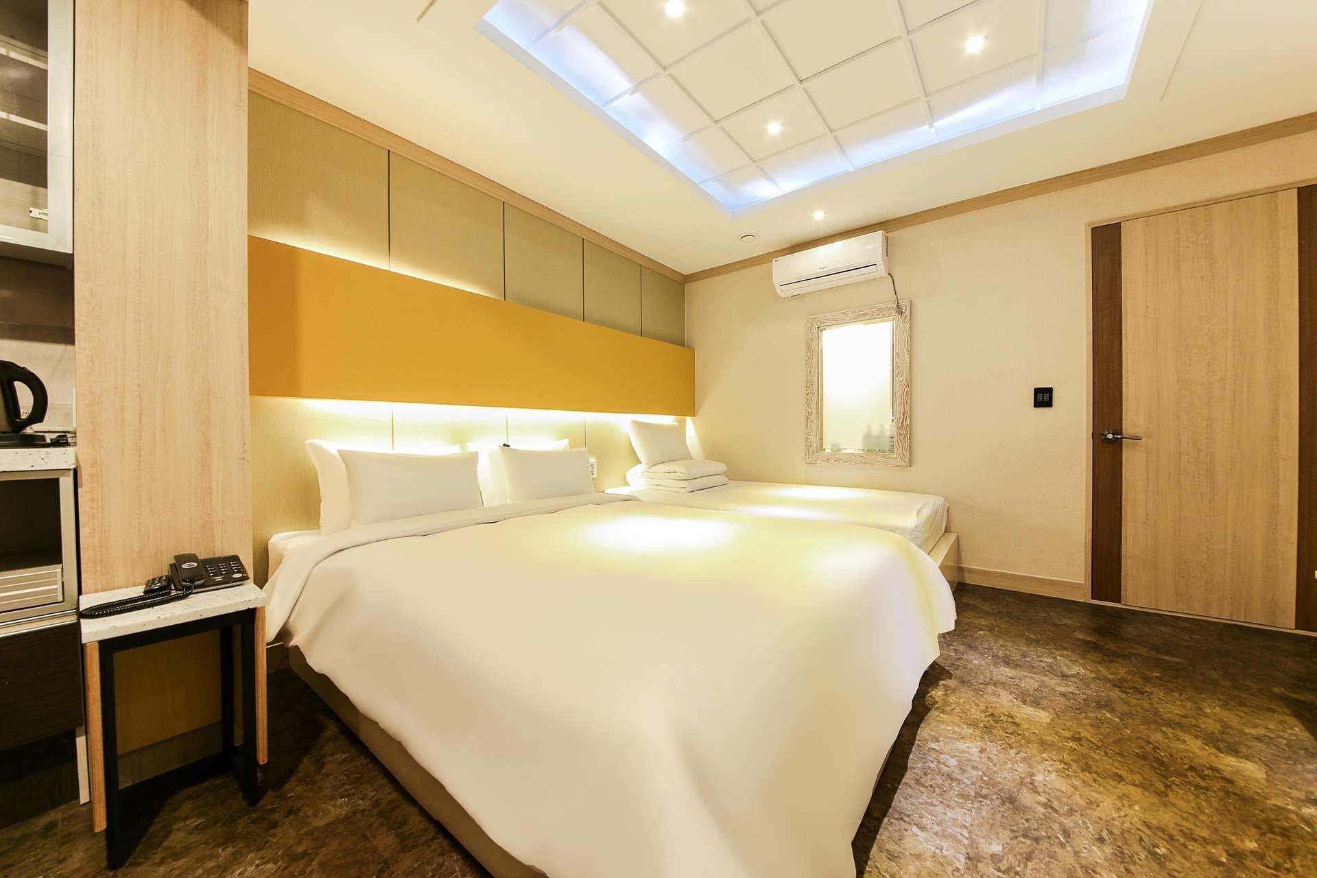 Une chambre d’hôtel moderne dotée d’un grand lit, d’un bureau avec un téléphone, d’une armoire et d’une fenêtre de toit.