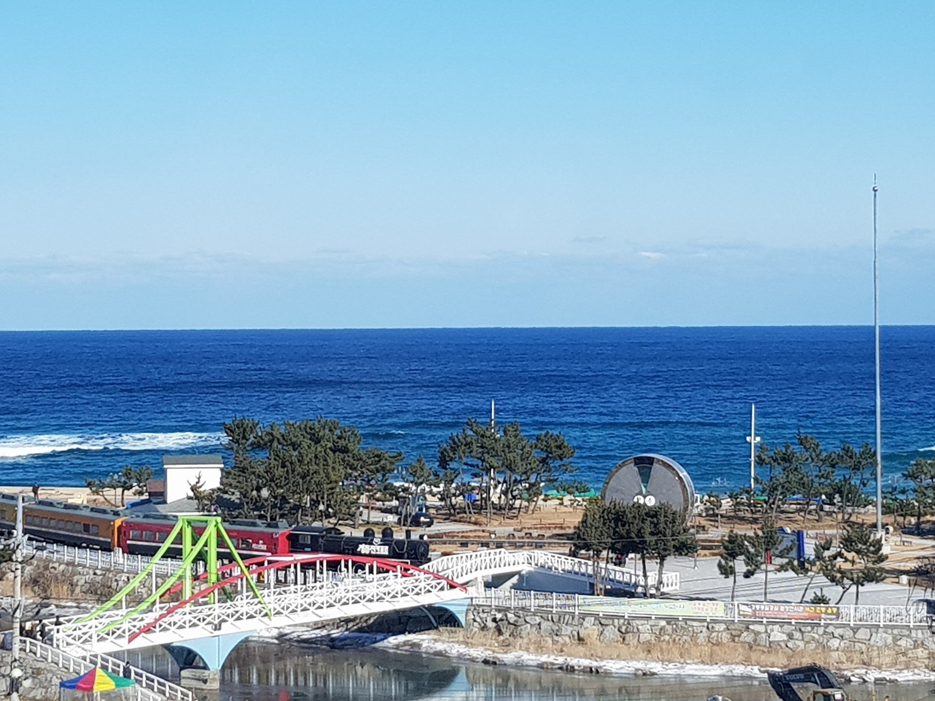 A coastal area with a bridge, a beach, and a body of water.