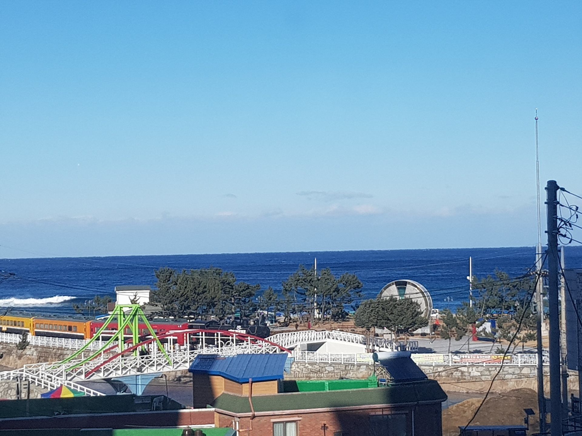 A coastal amusement park with a roller coaster, Ferris wheel, and various rides.