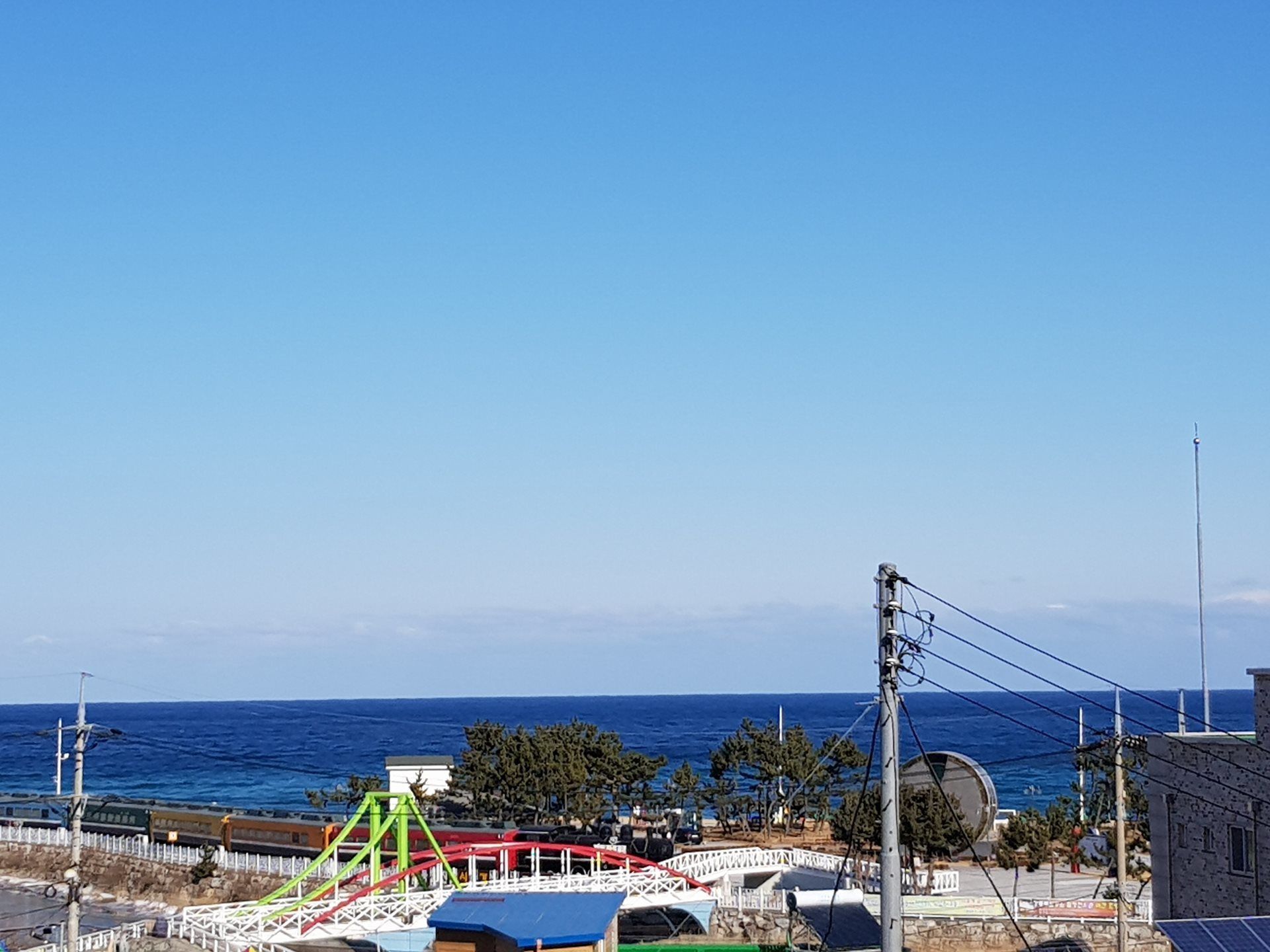 Une zone côtière dotée d’une aire de jeux, d’une clôture blanche et d’une vue sur la mer.