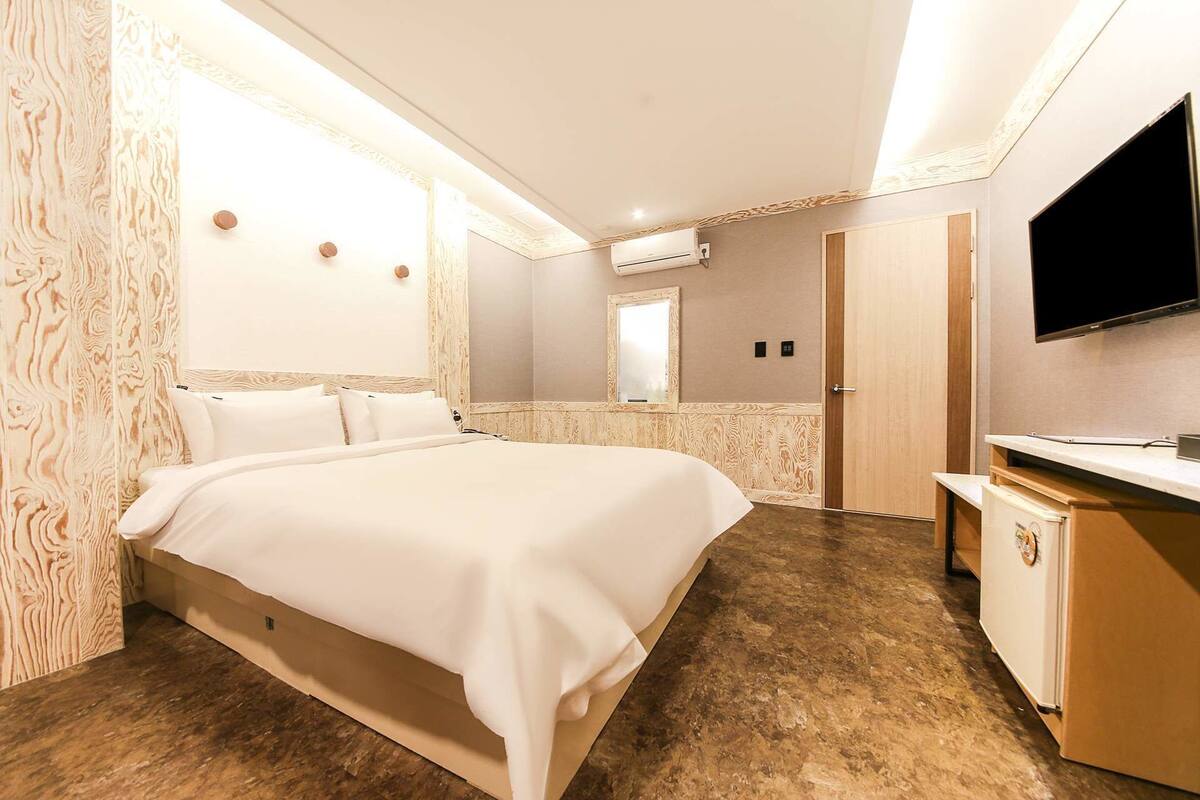 A hotel room with a bed, a TV, a mirror, and a wardrobe.