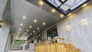 A modern interior with a wooden staircase, a skylight, and a tiled ceiling. - Hotel Tops Ville (Gangneung)