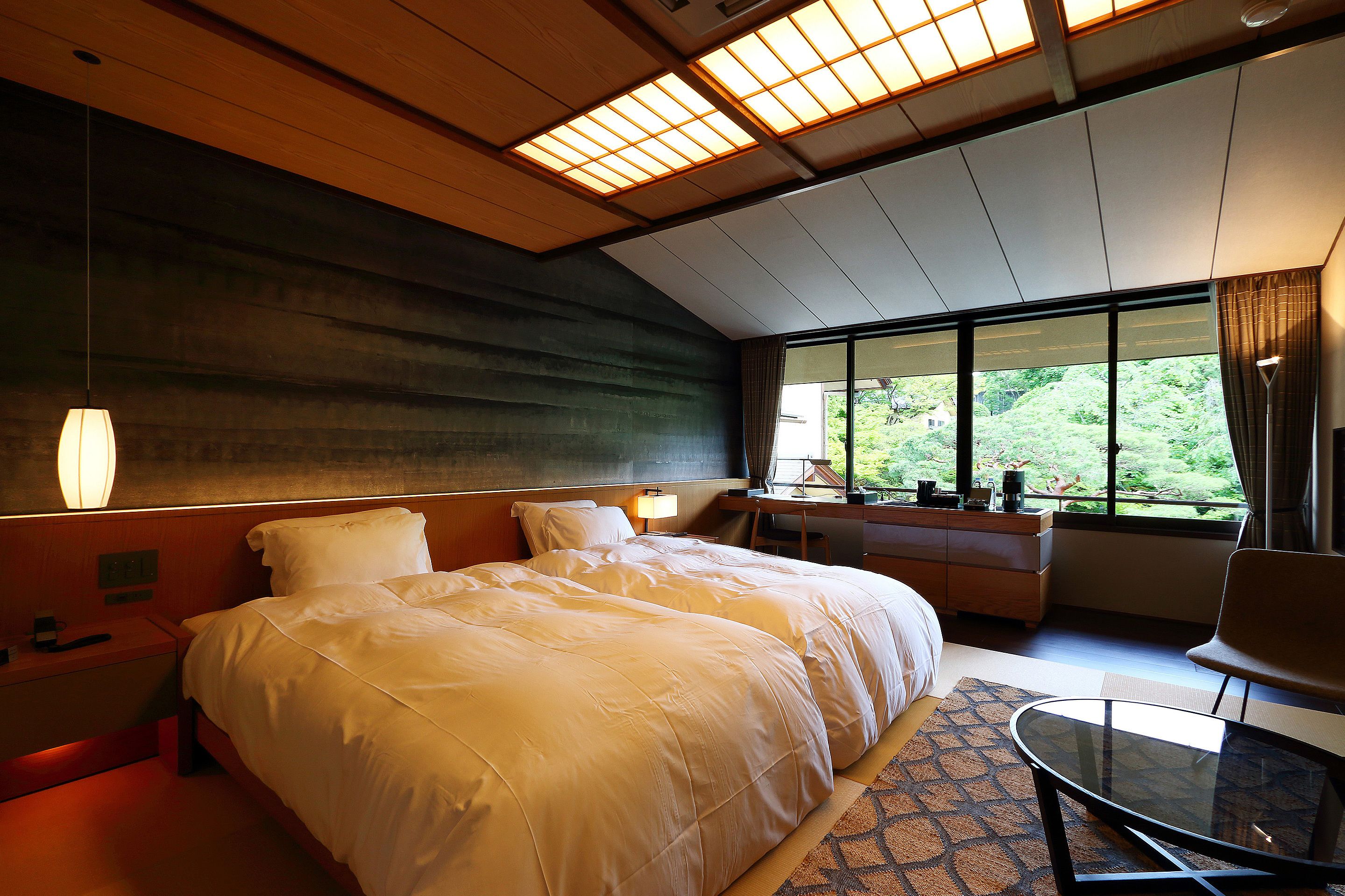 Ein Hotelzimmer mit einem großen Bett, einem Schreibtisch, einem Stuhl und Blick auf Grün.