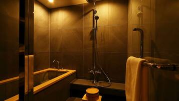 A modern bathroom with a bathtub, shower, and a wooden stool.