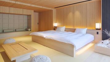 A modern bedroom with a large bed, bedside lamps, a wooden headboard, and a small table with a cushion.