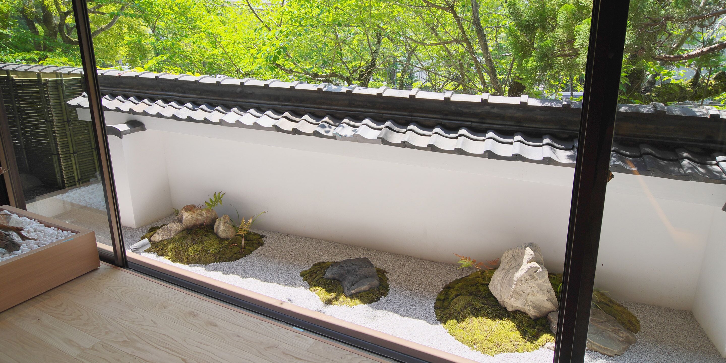 A traditional Japanese-style room with tatami flooring, a shoji screen, and a view of lush greenery outside.