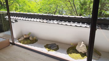 Una habitación tradicional japonesa con suelo de tatami, un celosía de papel y vistas a un exuberante follaje exterior.