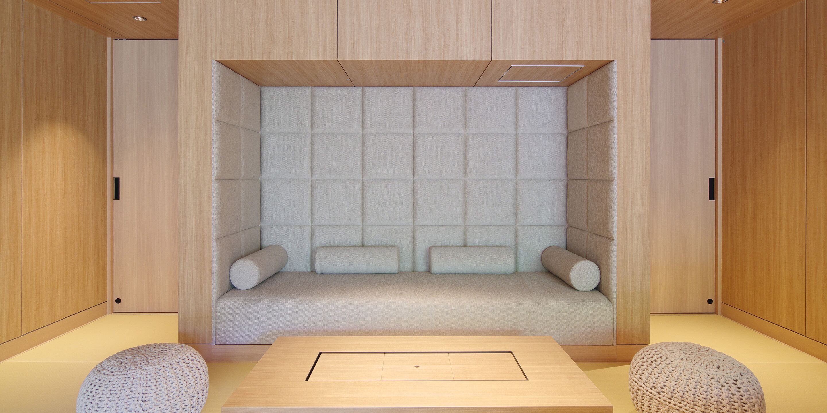 Een moderne kamer met een ingebouwde zithoek, houten wanden en een lichtgekleurde vloer.