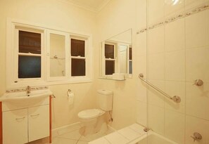Un baño con inodoro, lavamanos y zona de ducha.