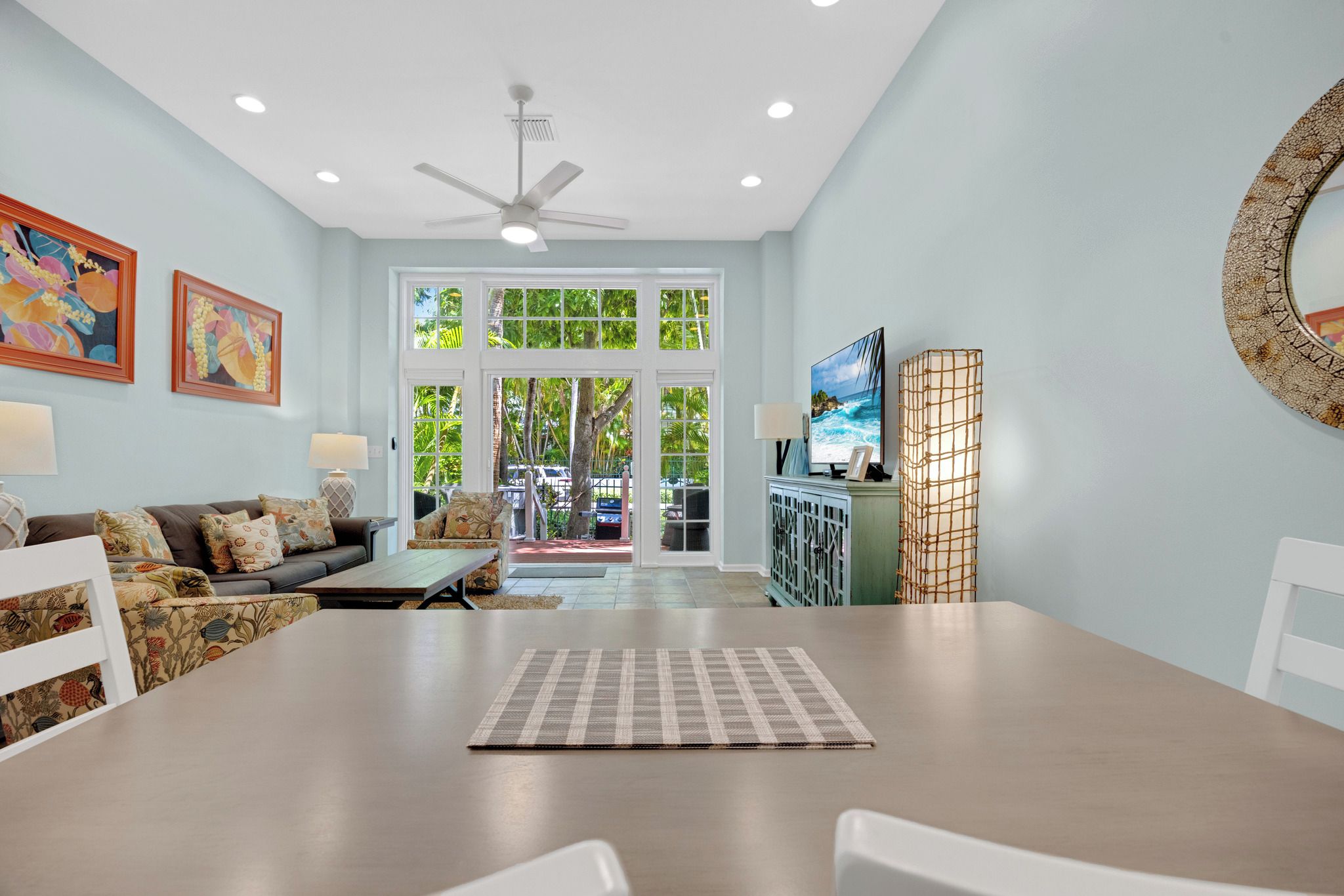 A spacious living room with a large dining table, a sofa set, and a television.