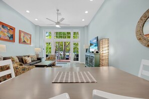 A spacious living room with a large dining table, a sofa set, and a television.