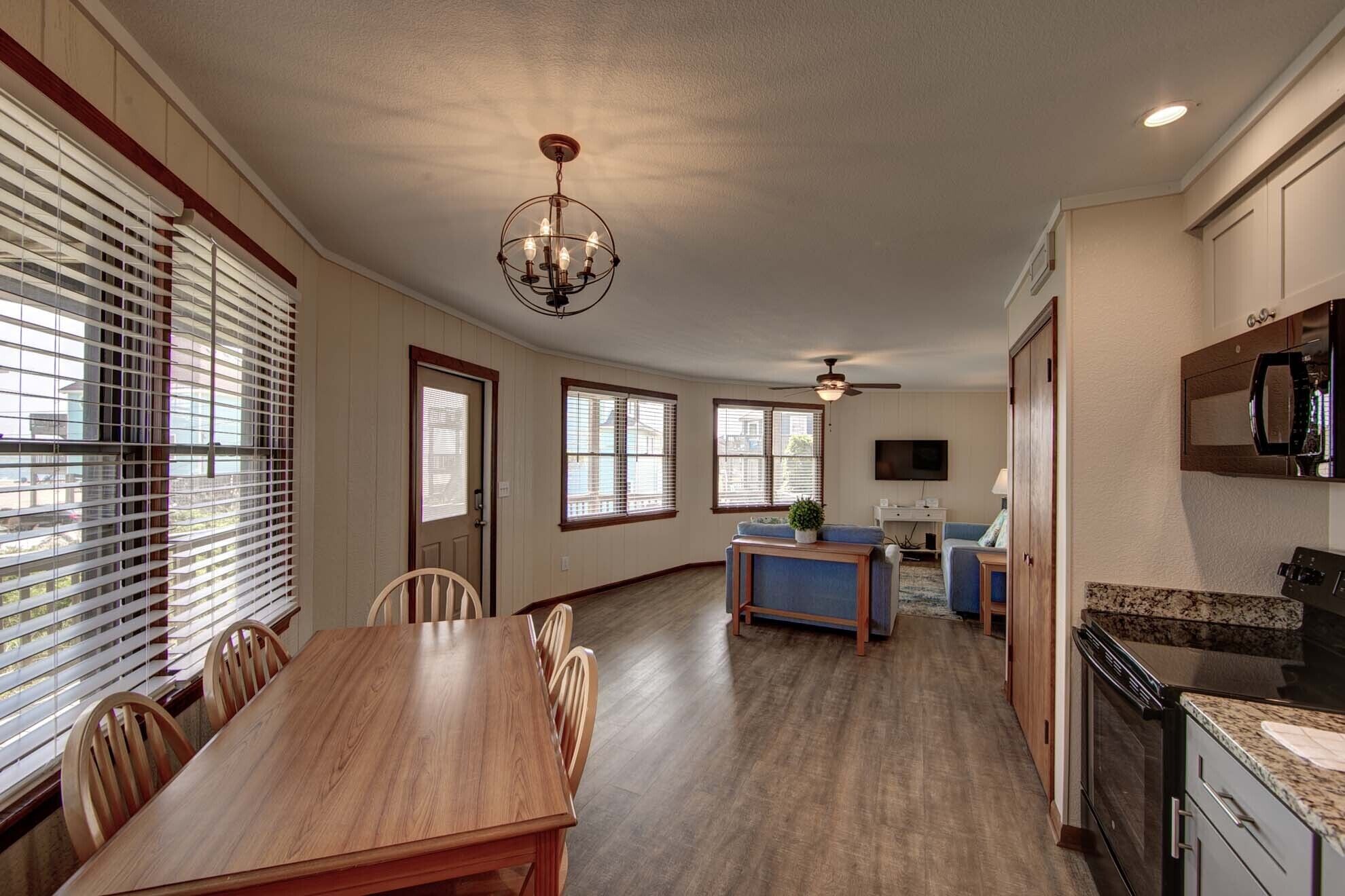 A spacious kitchen with a dining area, wooden flooring, and a ceiling fan.