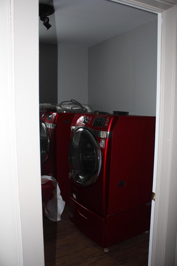 Une buanderie équipée de deux machines à laver rouges et d’un sèche-linge.