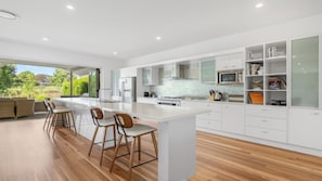 A modern kitchen with a large island, bar stools, and a view of the outdoors.