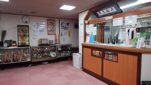 A reception area with a wooden counter, a clock on the wall, and various signs including a Wi-Fi availability sign.