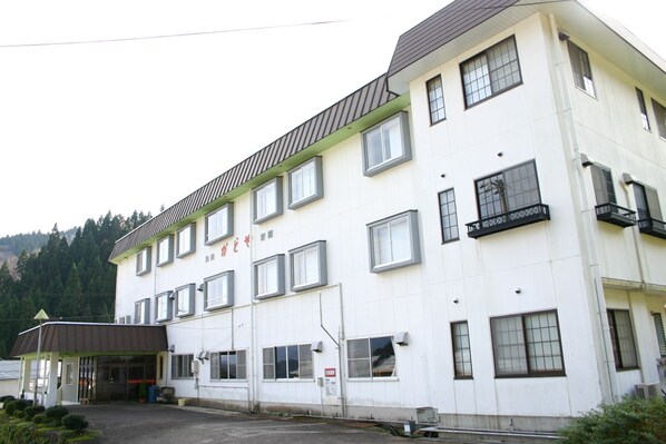 Een meerhoog gebouw met een plat dak, grote ramen en een bord met Japanse tekens.