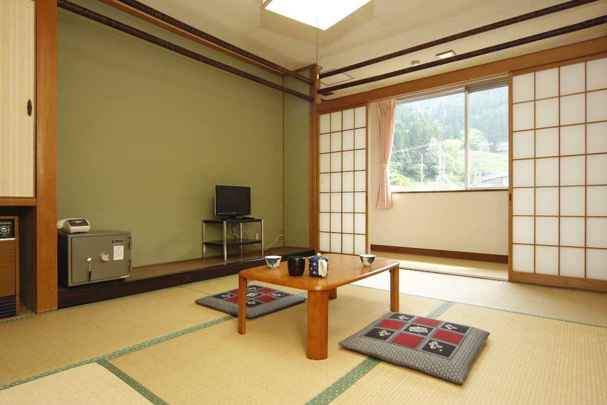 Een traditionele Japanse kamer met tatami vloeren, een lage houten tafel, een kluis en een televisie.