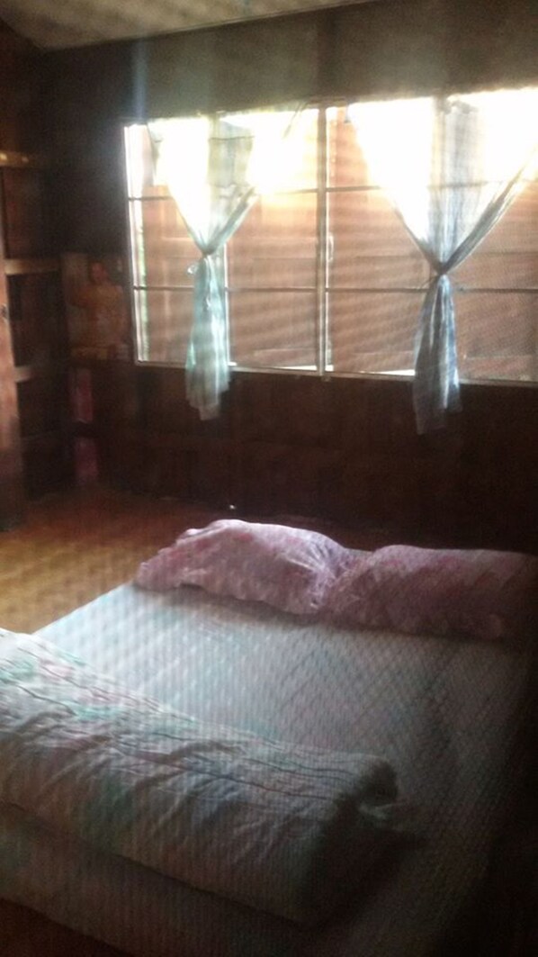 A room with a bed, wooden walls, and a window with curtains.