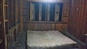 Simple, unadorned room with a single mattress and a window above.