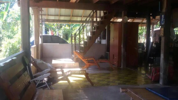 Un espacio al aire libre techado con un banco de madera, una mesa y una escalera que conduce a un nivel superior.