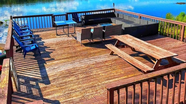 A wooden deck with outdoor seating and a view of a lake. - Lakefront, Hot Tub, Game Room, Canoe, Kayaks, Decks, Firepit (Tobyhanna)