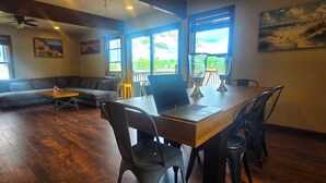 A spacious living area with a wooden dining table, comfortable seating, large windows, and artwork on the walls. - Lakefront, Hot Tub, Game Room, Canoe, Kayaks, Decks, Firepit (Tobyhanna)