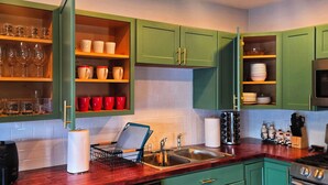 A kitchen with green cabinets, a stainless steel sink, and a microwave. - Lakefront, Hot Tub, Game Room, Canoe, Kayaks, Decks, Firepit (Tobyhanna)