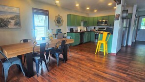 A kitchen with green cabinets, a wooden dining table, and a yellow stool. - Lakefront, Hot Tub, Game Room, Canoe, Kayaks, Decks, Firepit (Tobyhanna)