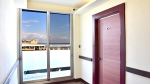 A corridor with a sliding glass door leading to a balcony with a view of the sea and buildings. - Fugong Hostel (Taitung)