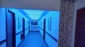 A hallway with a blue-lit ceiling and a long corridor with doors on either side. - Fugong Hostel (Taitung)