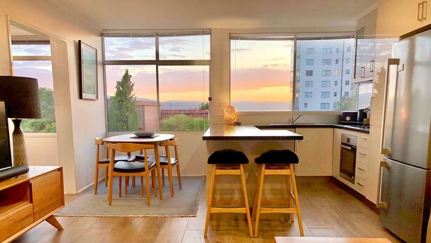 Cozinha moderna com uma janela ampla, móveis de madeira e vista para o pôr do sol.