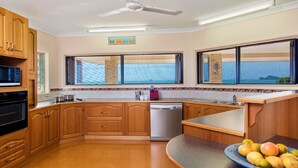 A kitchen with wooden cabinets, a dishwasher, a microwave, and a fruit bowl. - 'IslandView' The Perfect Holiday Home (Hideaway Bay)