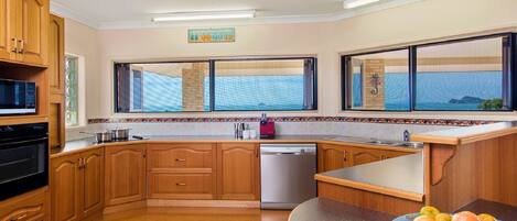 A kitchen with wooden cabinets, a dishwasher, a microwave, and a fruit bowl.