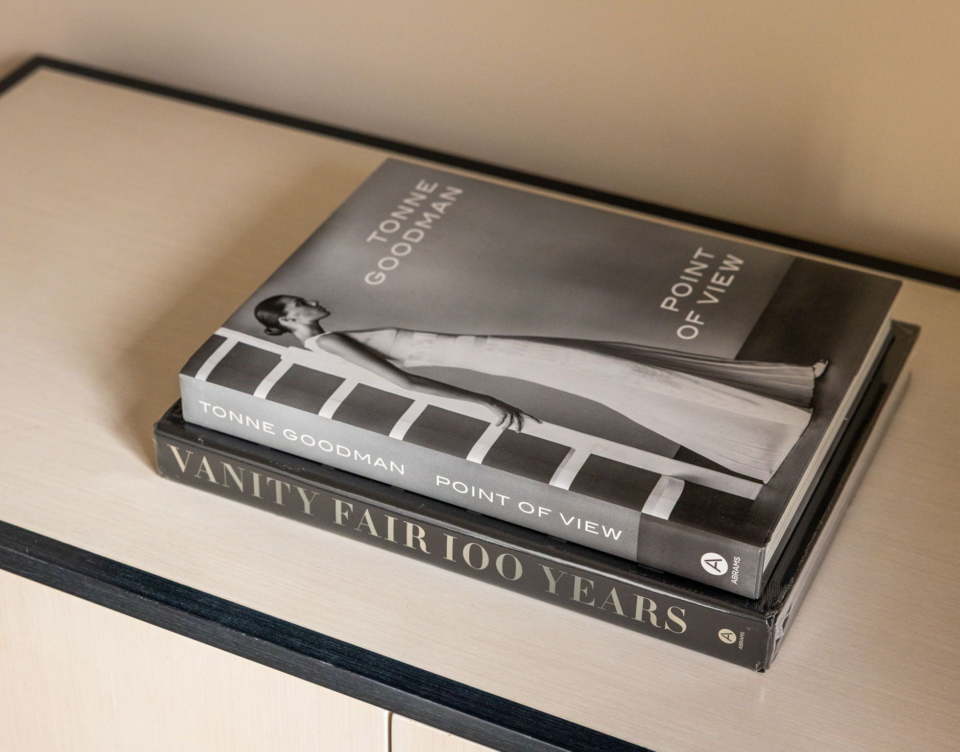 A stack of books titled 'VANITY FAIR 100 YEARS' and 'POINT OF VIEW' by TONNE GOODMAN.
