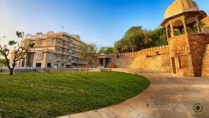 A historic building with a large central courtyard, a domed structure, and a multi-story building with balconies. - Fateh Niwas (Udaipur)