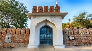 A stone wall with a blue door and a small flag on top. - Fateh Niwas (Udaipur)