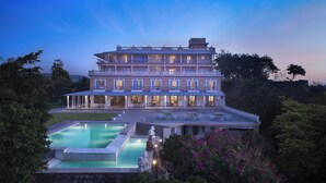 Un grand hôtel à plusieurs étages, doté d’une piscine et d’un espace extérieur aménagé avec des sièges.