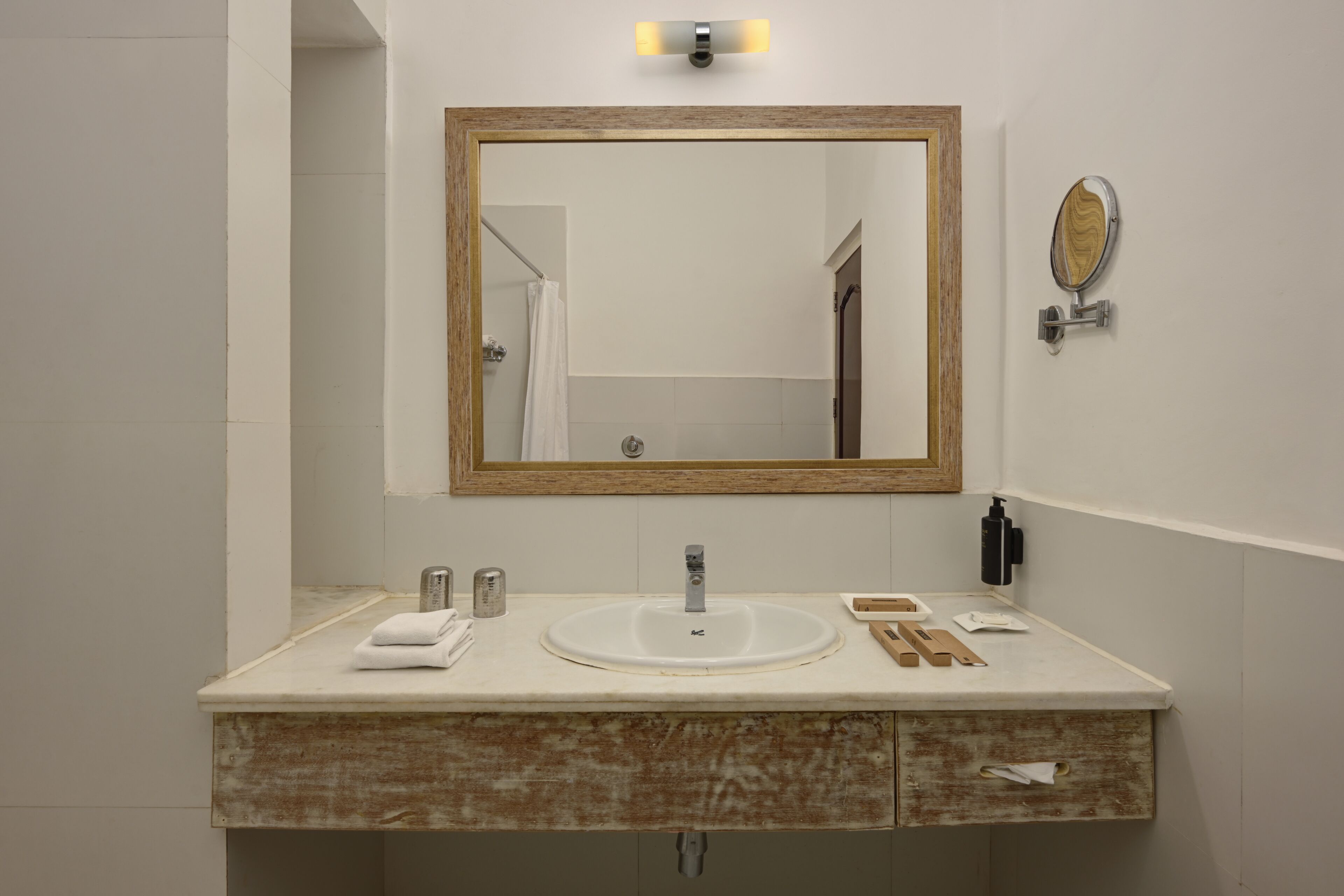 A bathroom with a large mirror, a sink, a towel, and a soap dispenser.