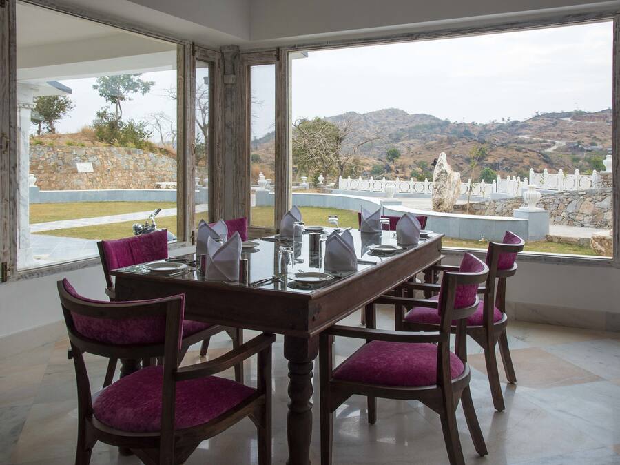 Comedor con una mesa dispuesta para seis personas, ventanas amplias y vistas a un paisaje montañoso.