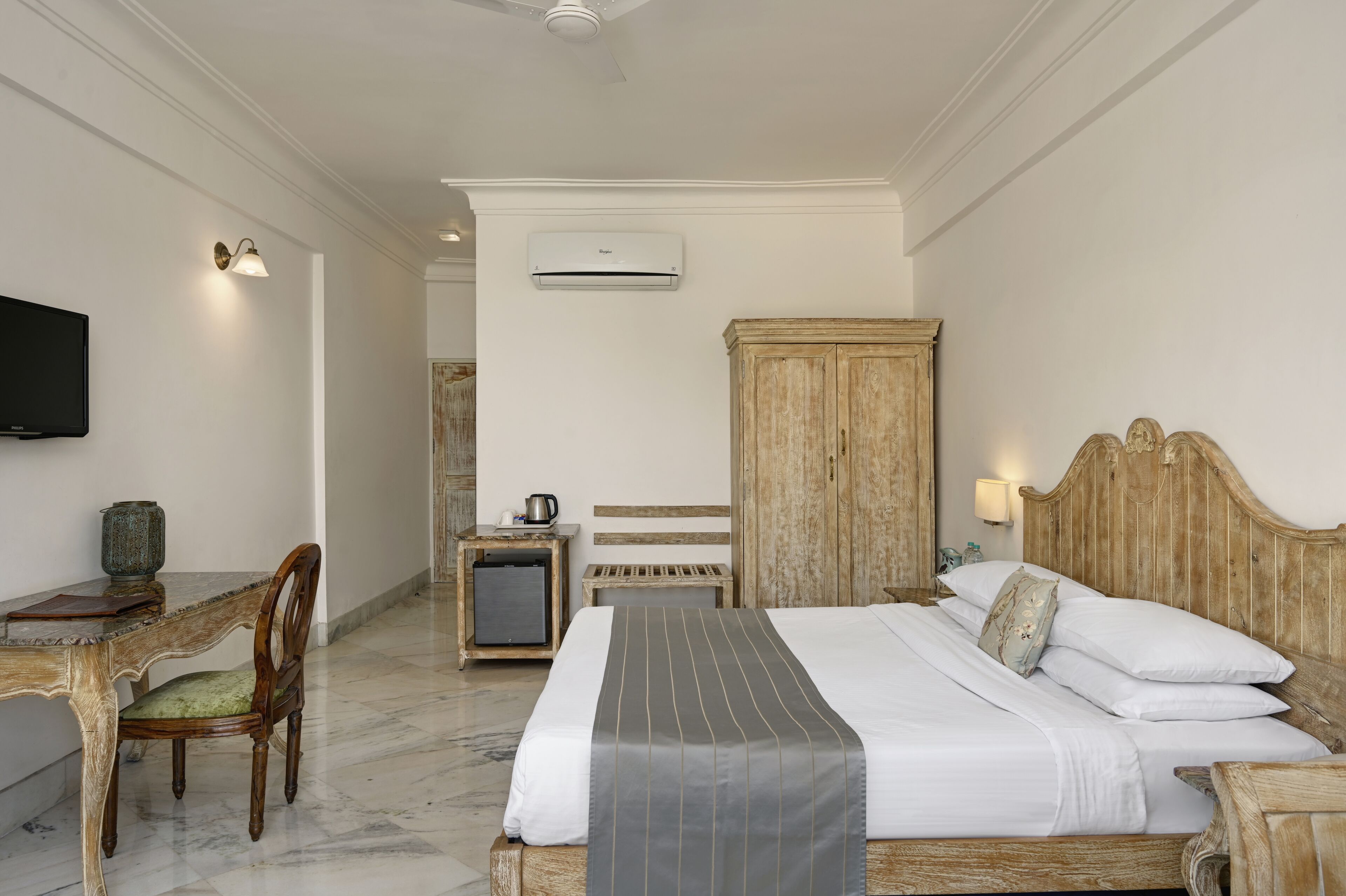 Habitación de hotel con cama, escritorio con silla, televisión, aire acondicionado y armario.