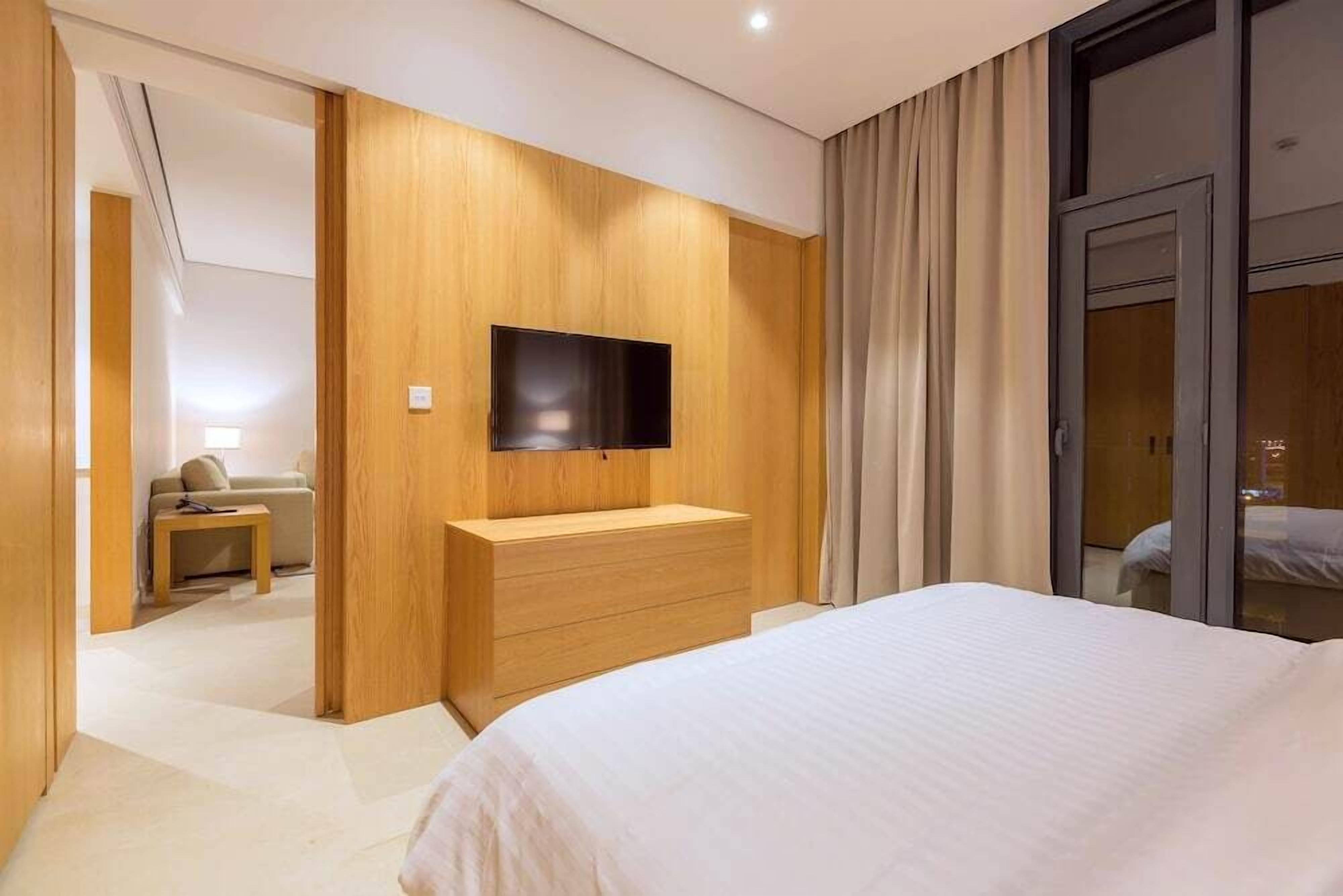 A hotel room with a large bed, wooden paneling, a flat-screen TV, and a sliding glass door.