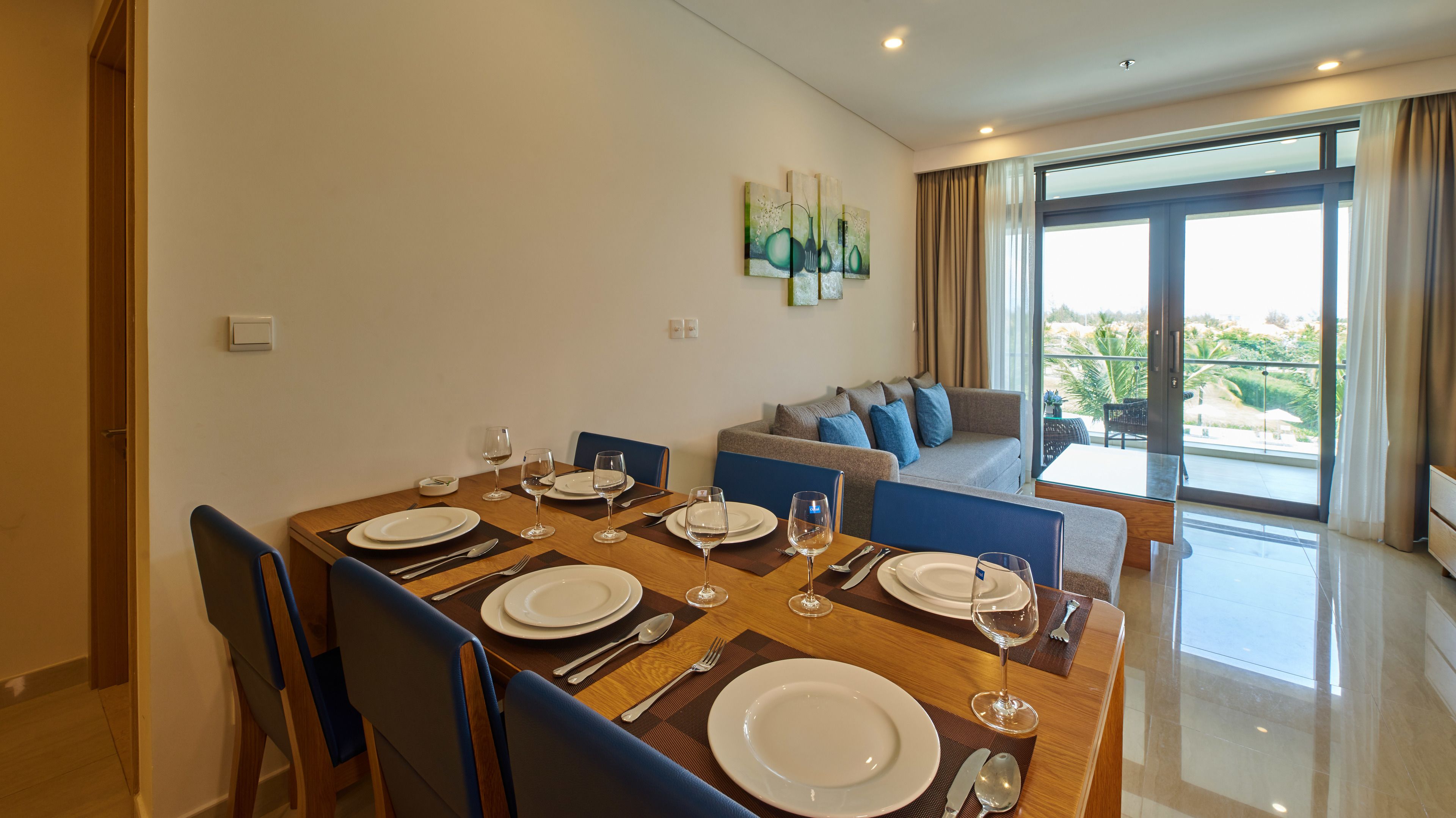 A dining area with a table set for four, a sofa, and a balcony with a view.