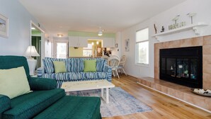 A living room with a green sofa, a striped sofa, a white coffee table, and a fireplace.