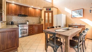 Una cocina con armarios de madera, estufa, refrigerador y una mesa de comedor con sillas.