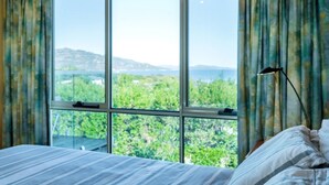 Un dormitorio con un ventanal que ofrece vistas a la vegetación y colinas.