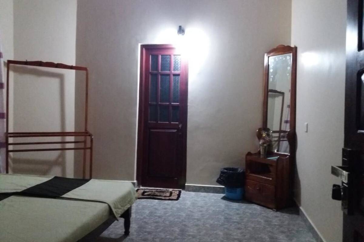 A bedroom with a bed, a wardrobe, a mirror, and a door.